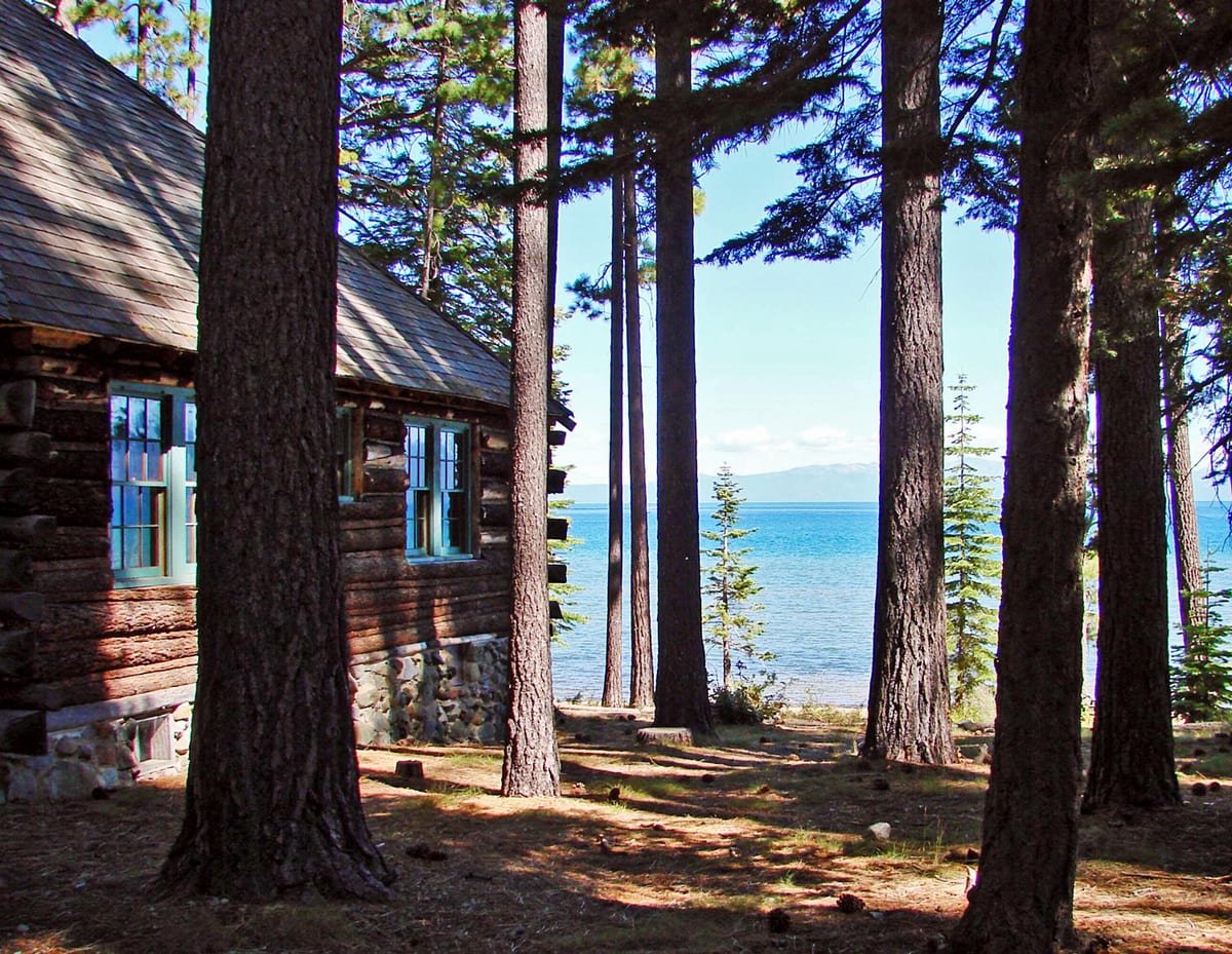 Lake cottage among tall trees at the edge of the water